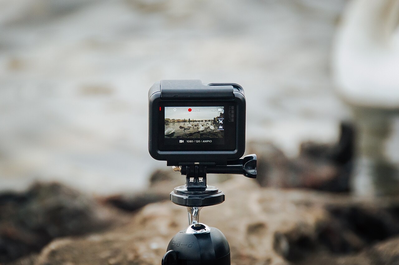 A small video camera mounted on a tripod with its rear screen visible.