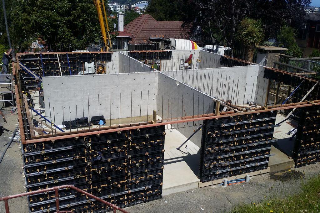 Concrete walls with formwork and reinforcing bars on a building site.