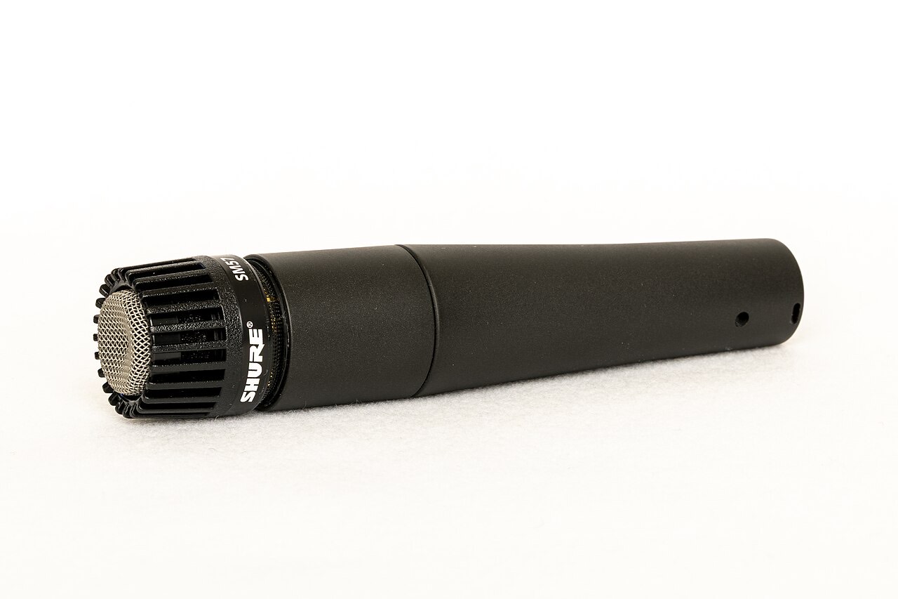 A black Shure microphone resting on a white surface.