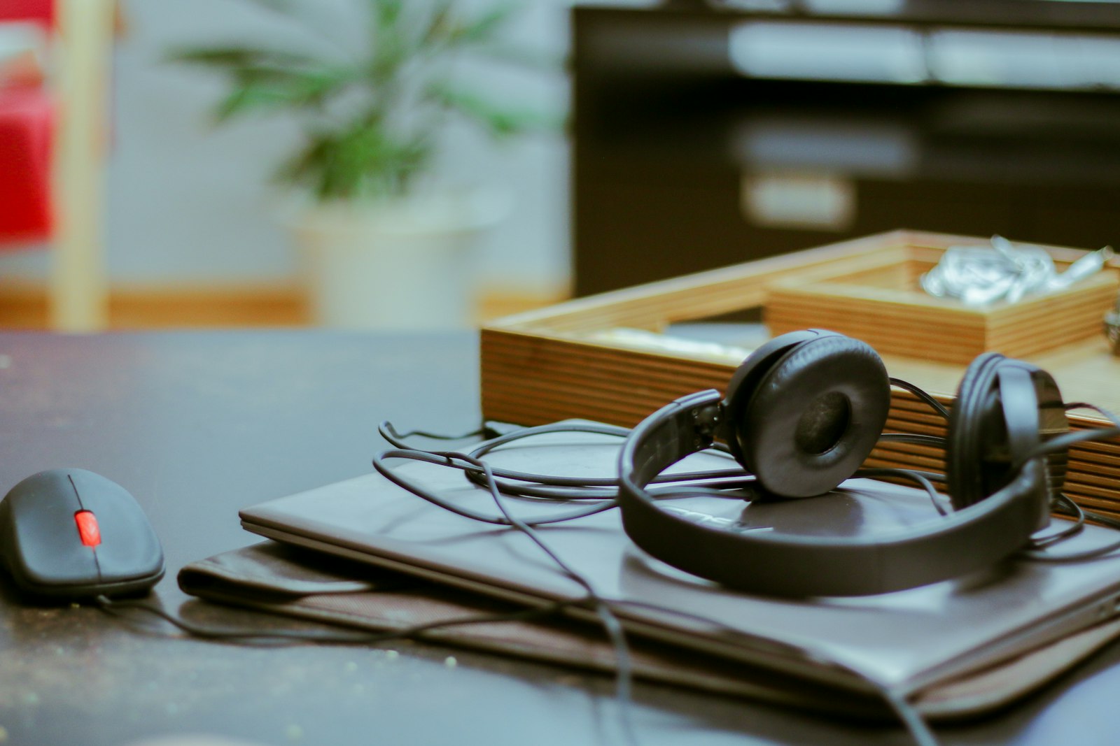 Black headphones resting on a closed laptop beside a mouse.