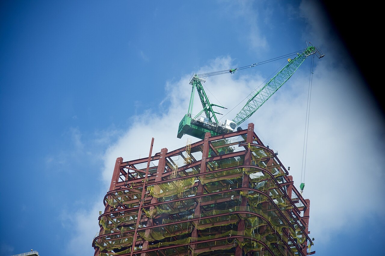A tower crane above the steel frame of a building under construction.